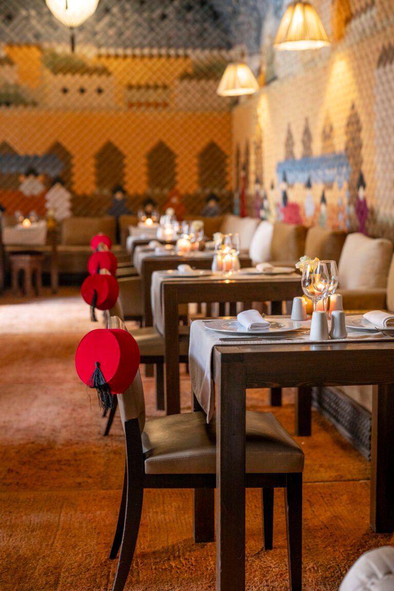 Candlelit restaurant interior at Almaha Marrakech with traditional Moroccan fez hats and zellige decor