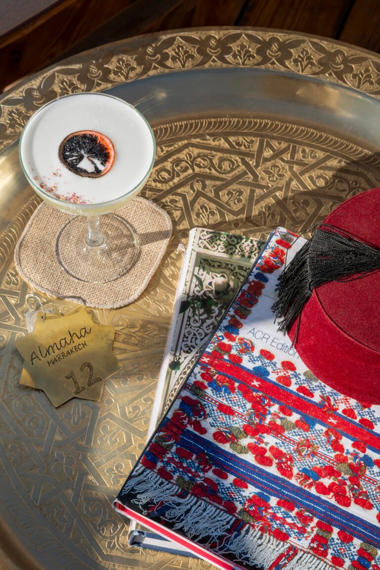 Diners enjoying lunch on a sunny rooftop terrace in Marrakech with a clear view of the snow-capped Atlas Mountains