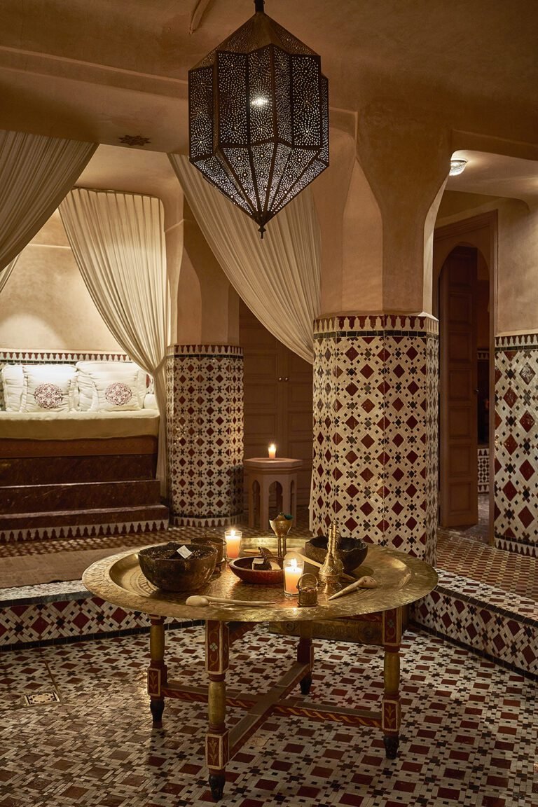 Traditional Moroccan spa relaxation area at Almaha Marrakech, featuring zellige tilework, a brass tea table, and a large ornamental lanterns.