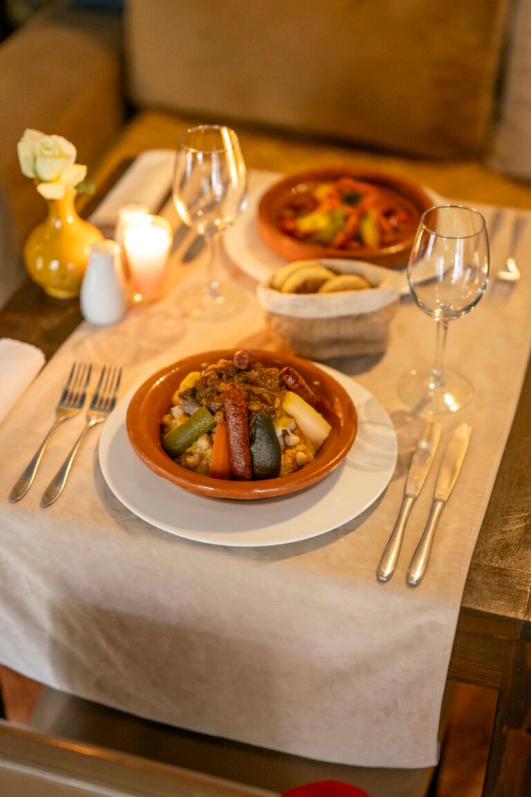 Close-up of a traditional Moroccan vegetable couscous served in a clay dish on a candlelit table at Almaha Marrakech
